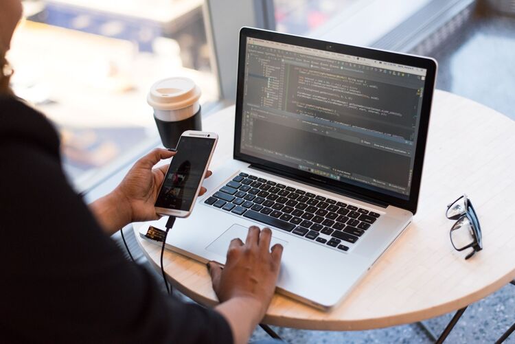 Canva Person Looking At Phone And At Macbook Pro Small